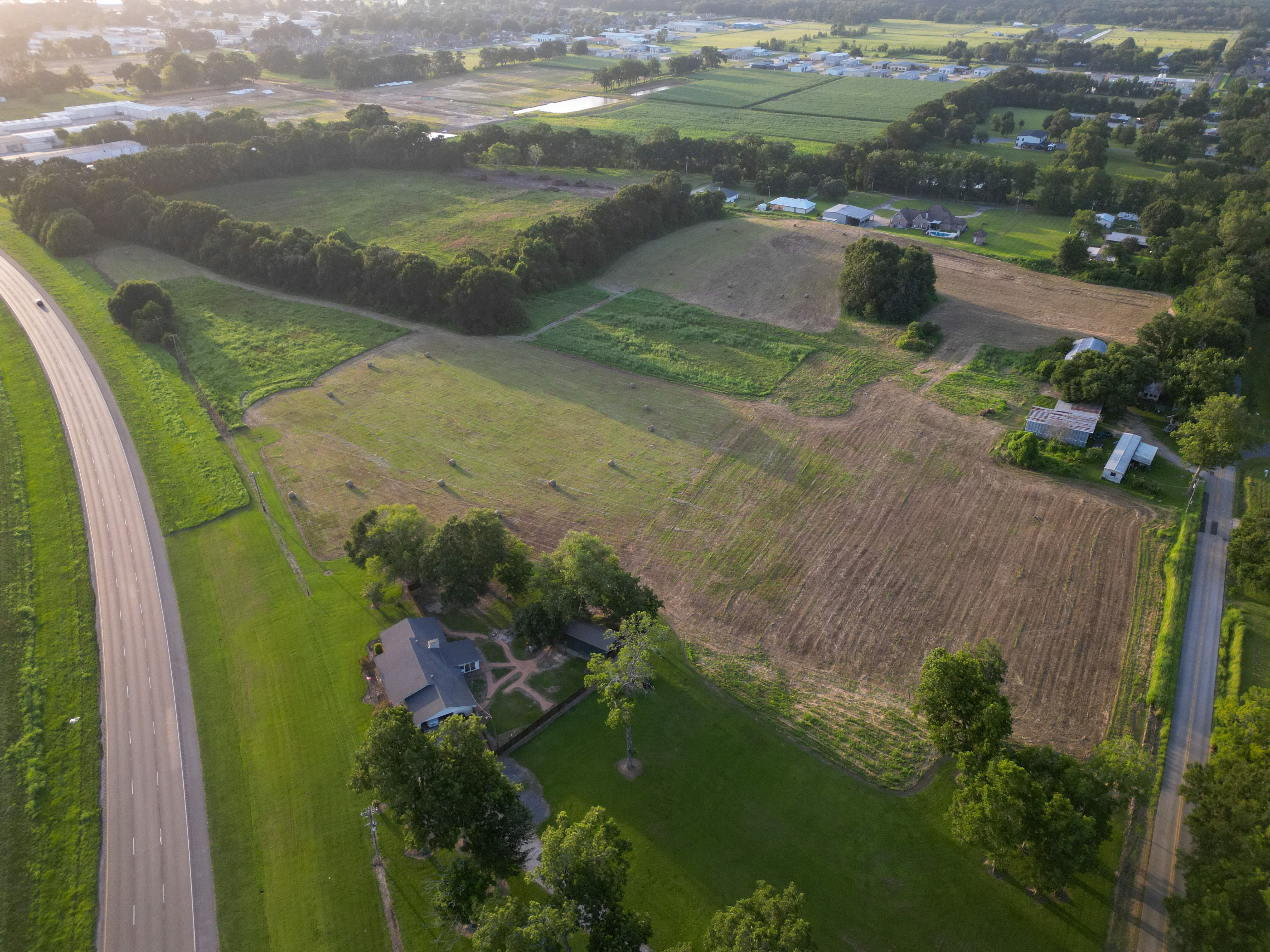 Drone shot showing full acreage, hay bales, and structure on the property