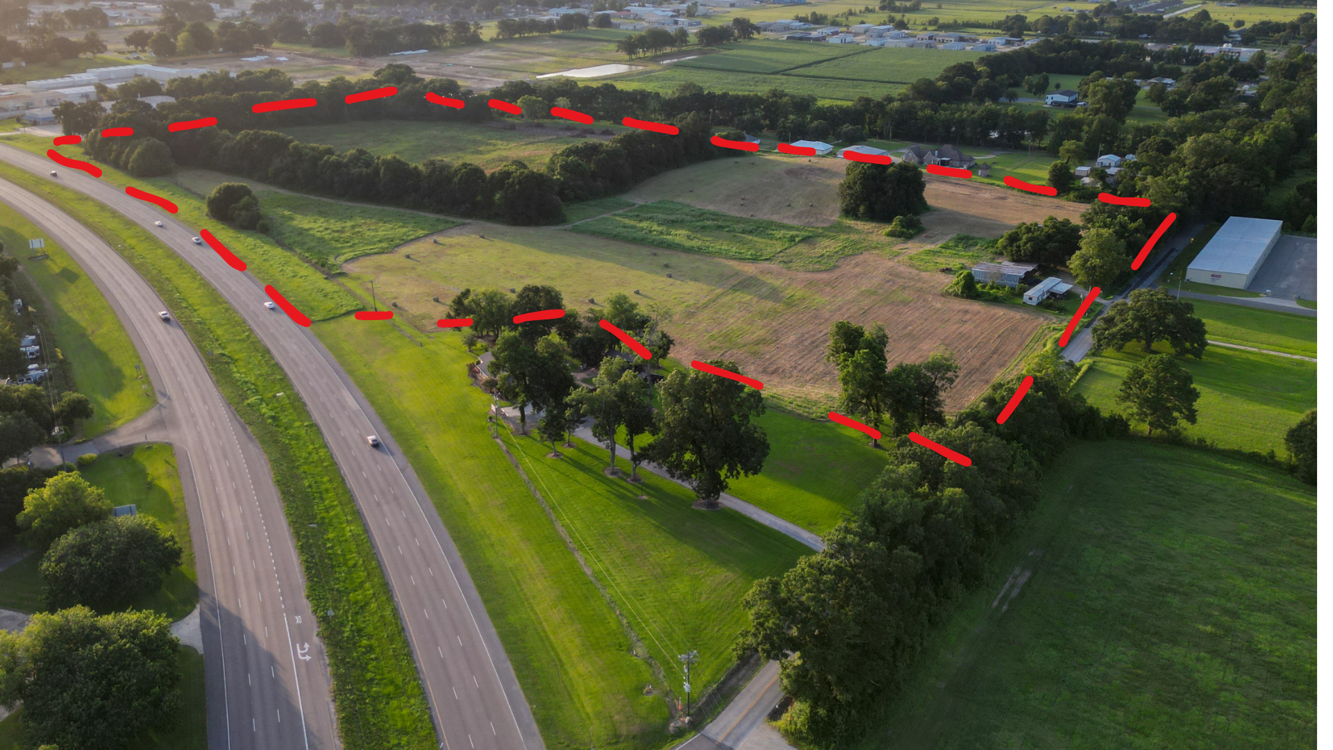 Aerial drone photo with red dashed line showing the full 34.4-acre property boundary along US Hwy 90